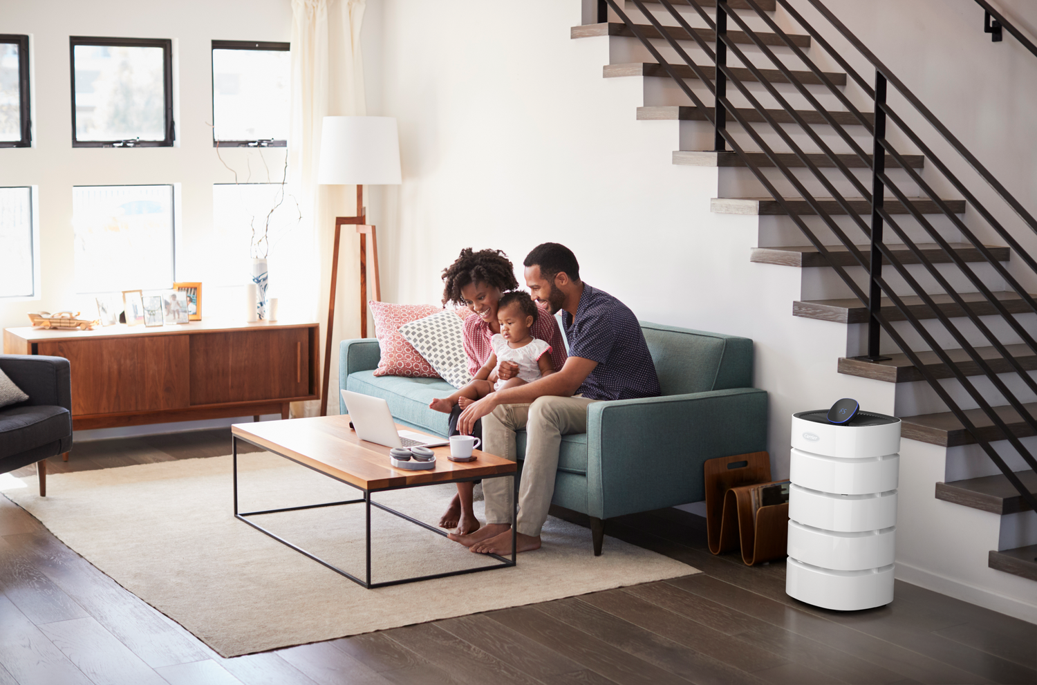 Parents and their child in their living room with the Carrier Air Purifier on